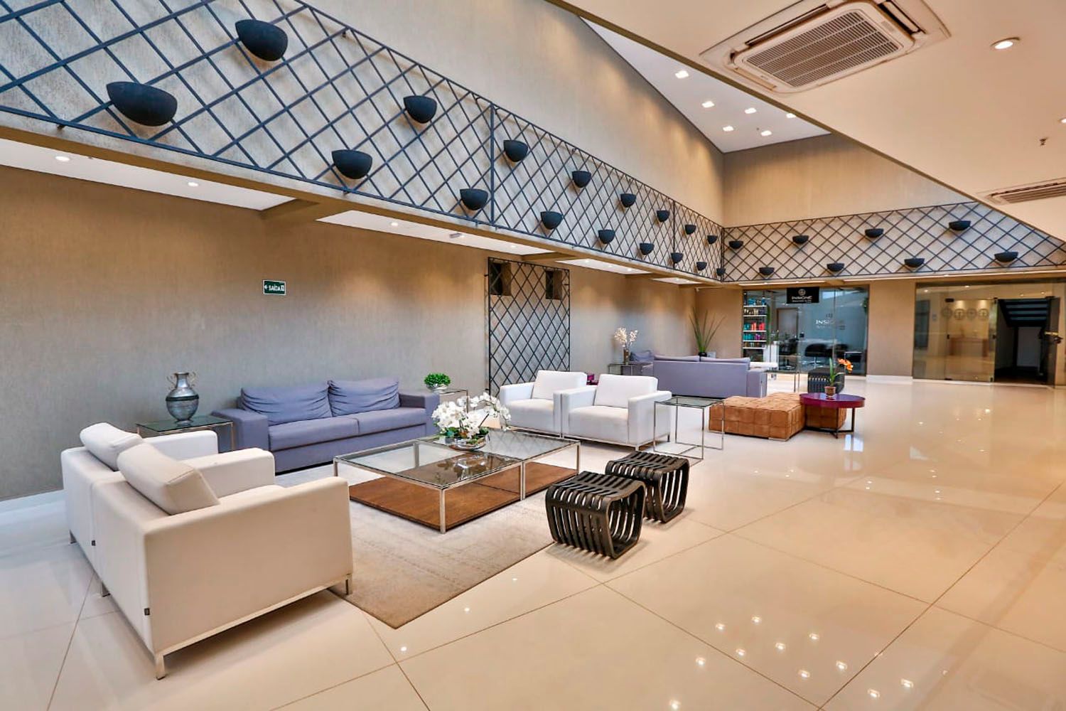 Um lobby de hotel com um sofá, cadeiras e uma mesa de centro.