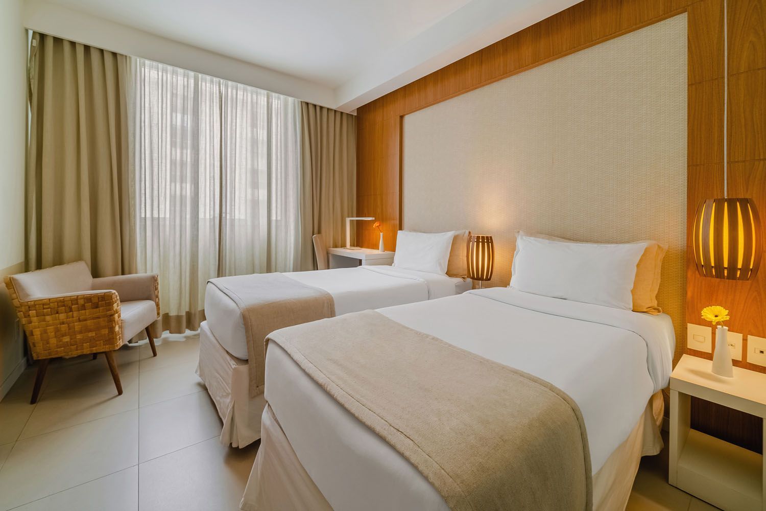 Um quarto de hotel com duas camas e uma cadeira.