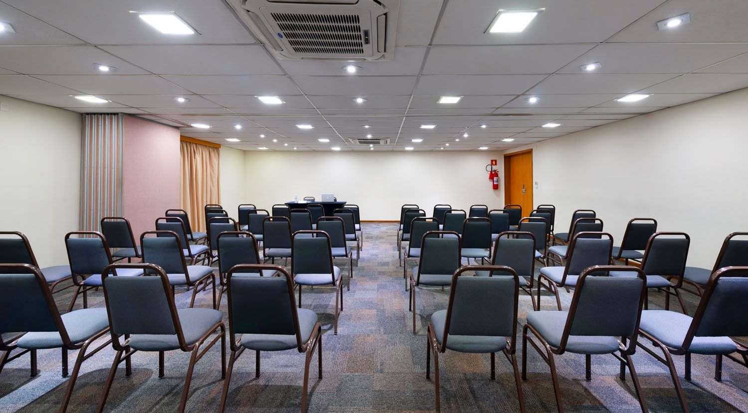 Uma sala de conferências com uma mesa redonda, cadeiras e uma TV de tela plana.