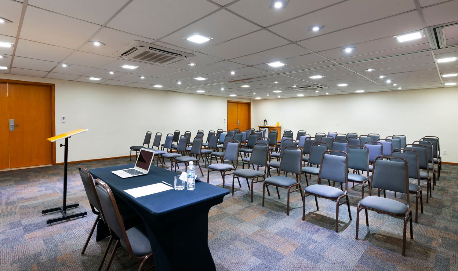 Uma grande sala de conferências com mesas e cadeiras e um pódio.