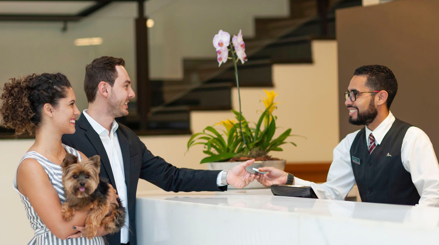 Um homem está dando uma chave para uma mulher enquanto segura um cachorro.