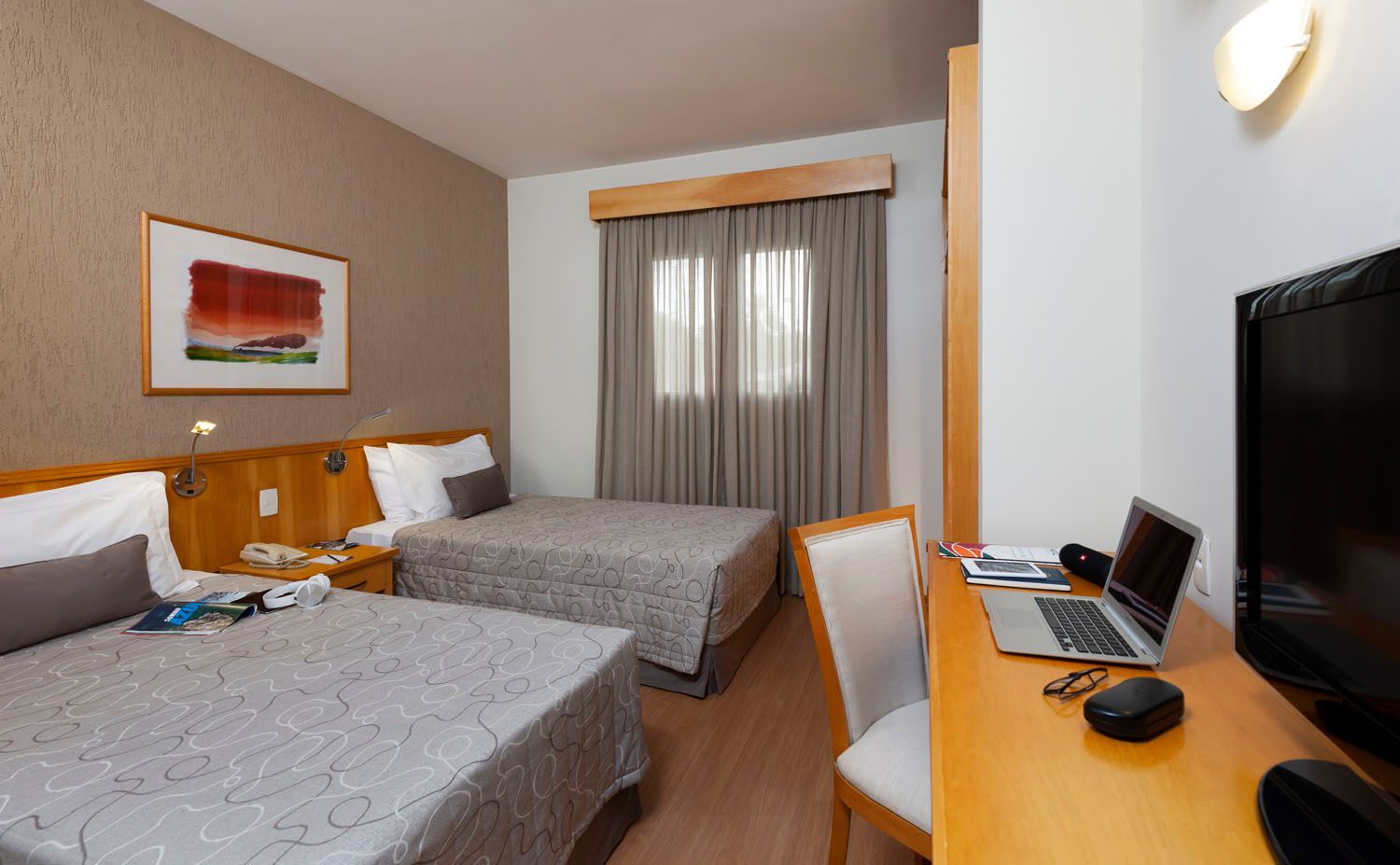 Um quarto de hotel com duas camas e uma mesa com um laptop