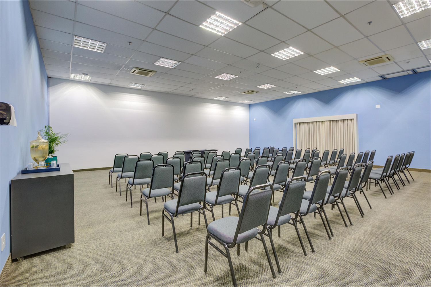 Uma sala de conferências com fileiras de cadeiras e uma tela de projetor.