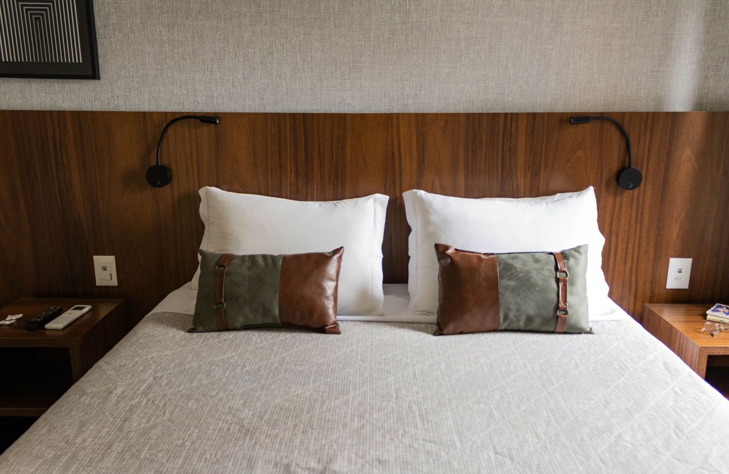 Uma cama com dois travesseiros e uma cabeceira de madeira.