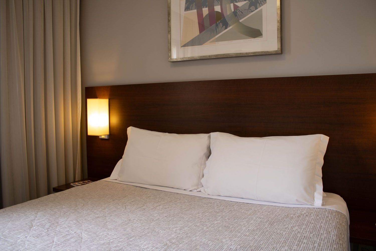 Um quarto de hotel com uma cama king size e um quadro na parede acima dela.