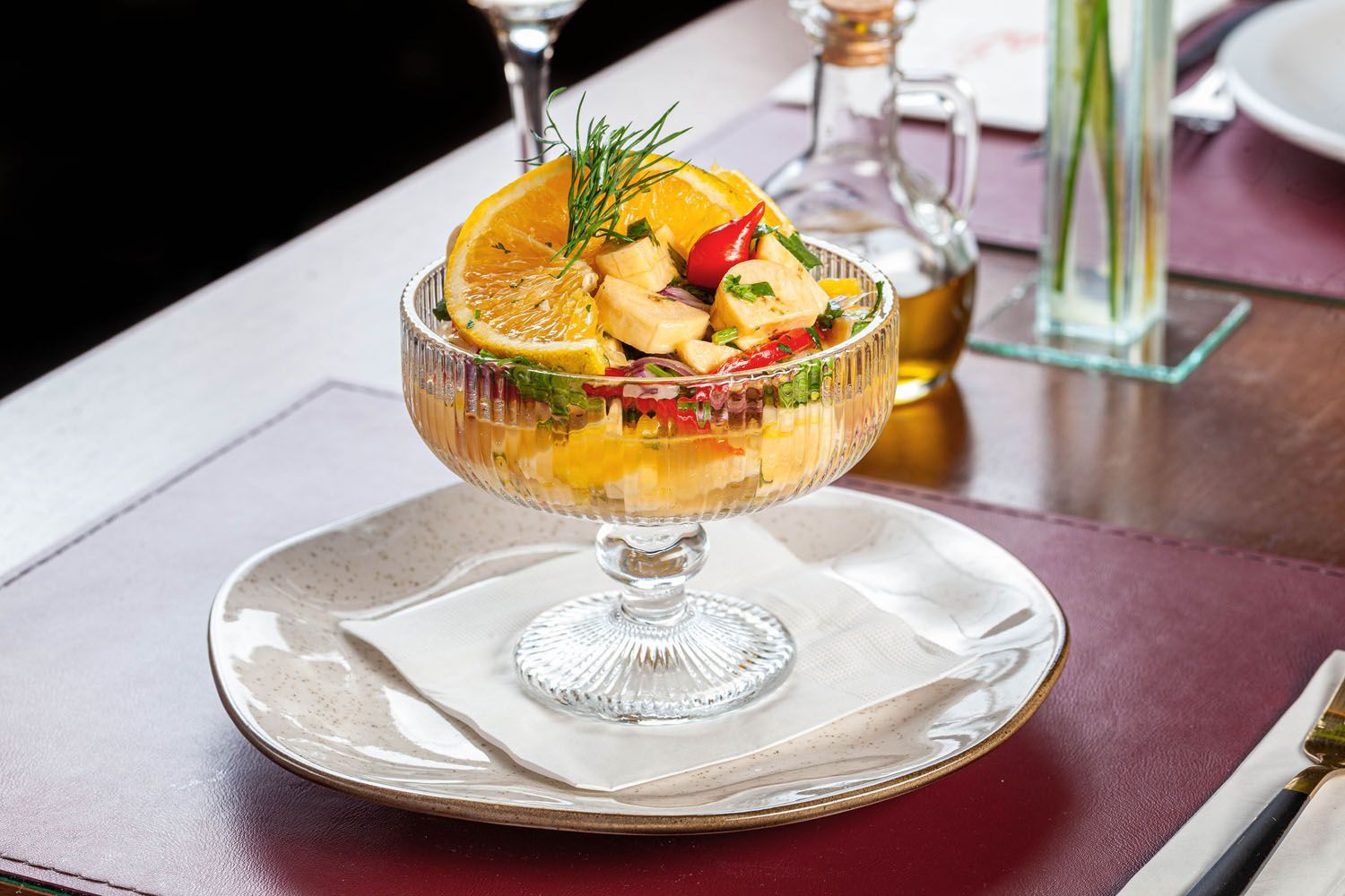 Uma salada em uma tigela de vidro em um prato sobre uma mesa.