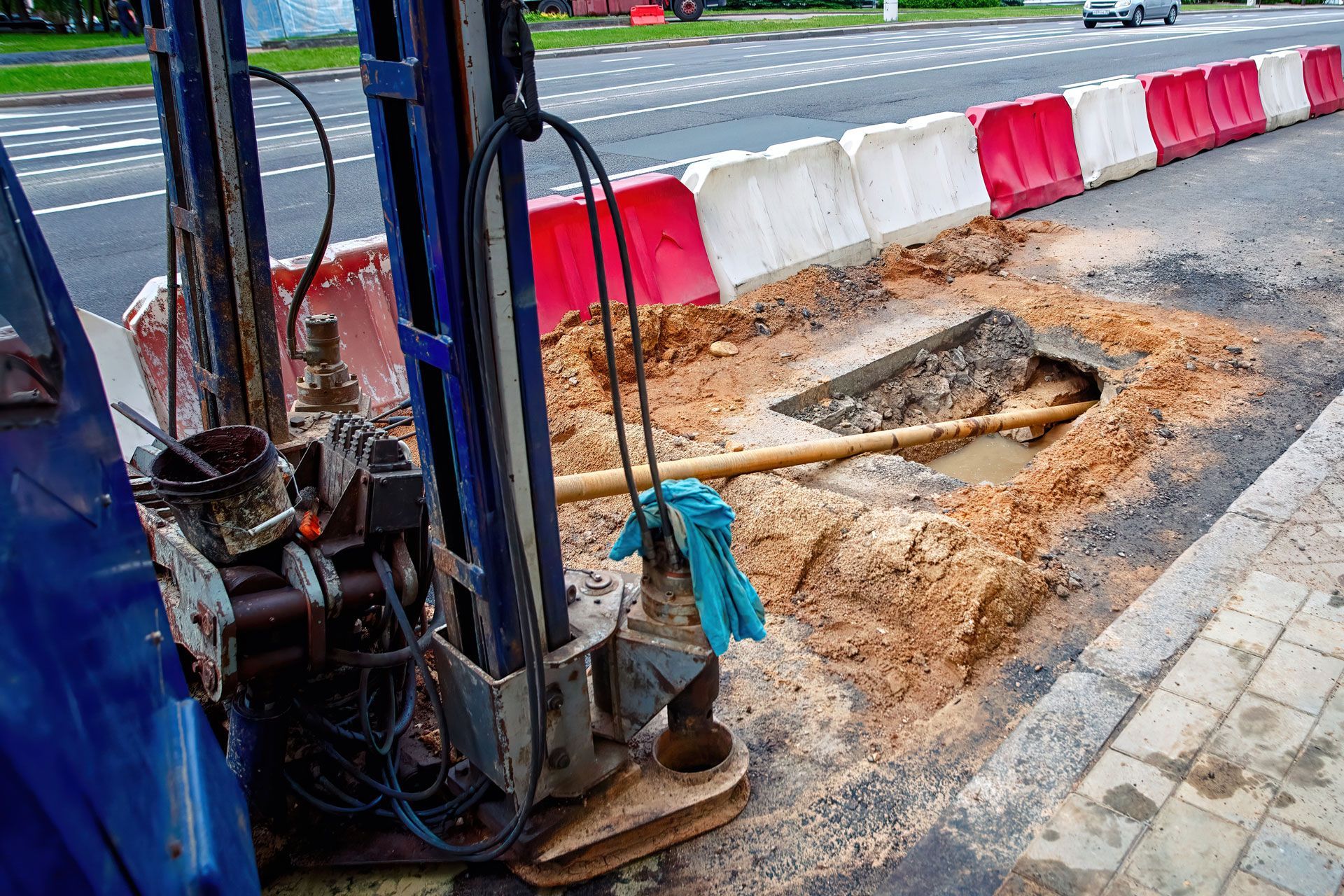 Yellow construction vehicle drilling pipe into the ground at a construction site