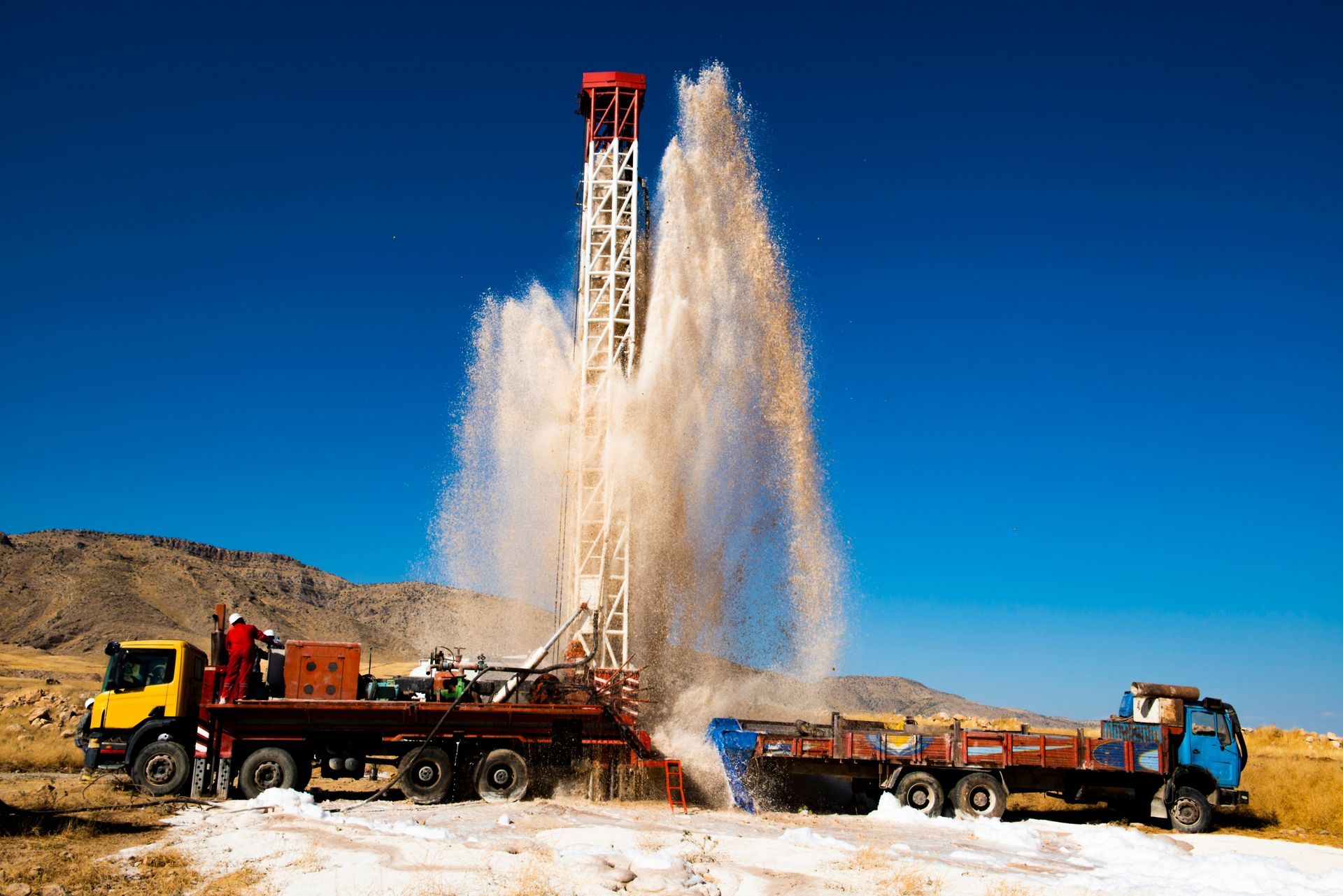 Drilling rig erupts water against a blue sky