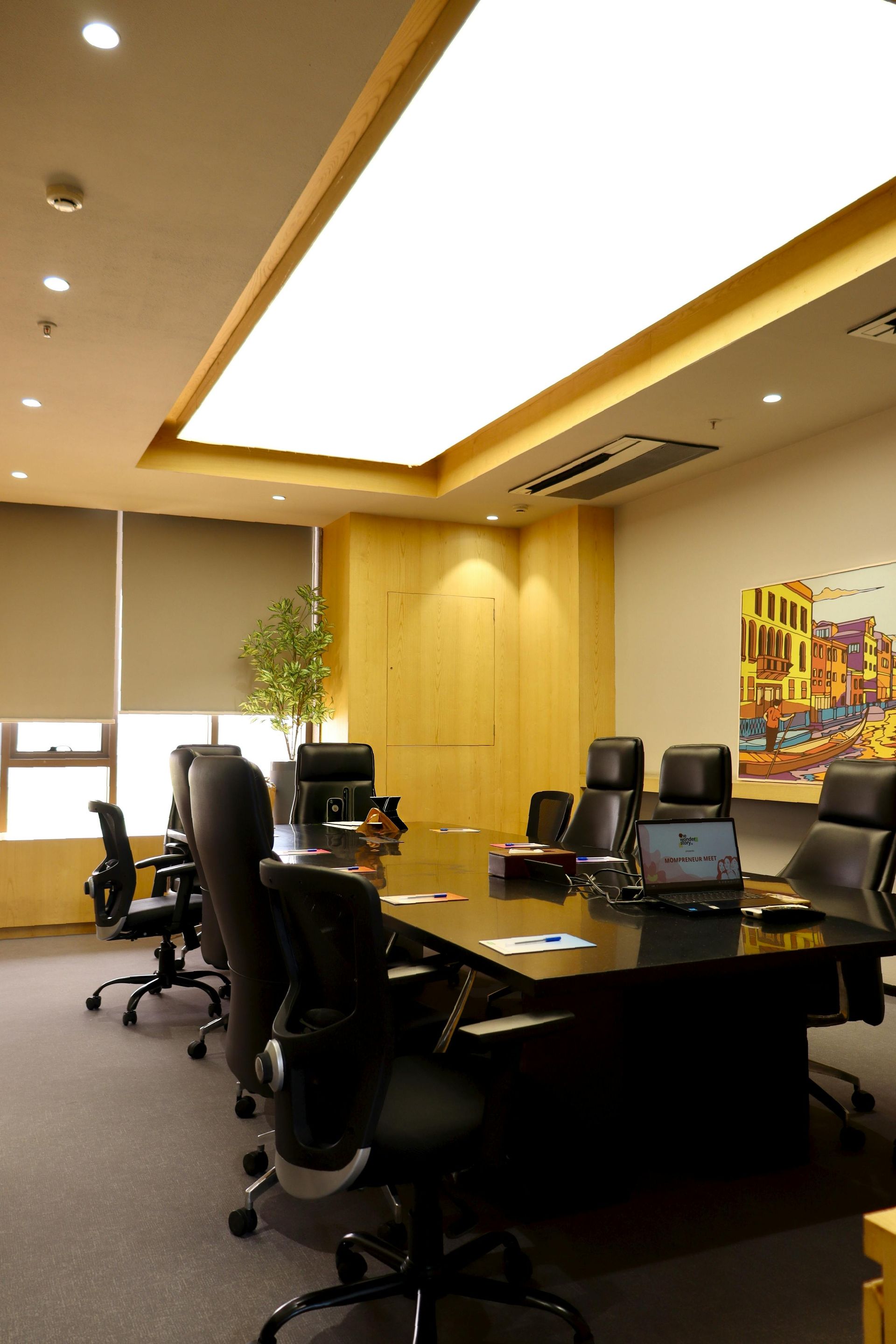 Conference room with dark table, black chairs, and bright ceiling lighting.