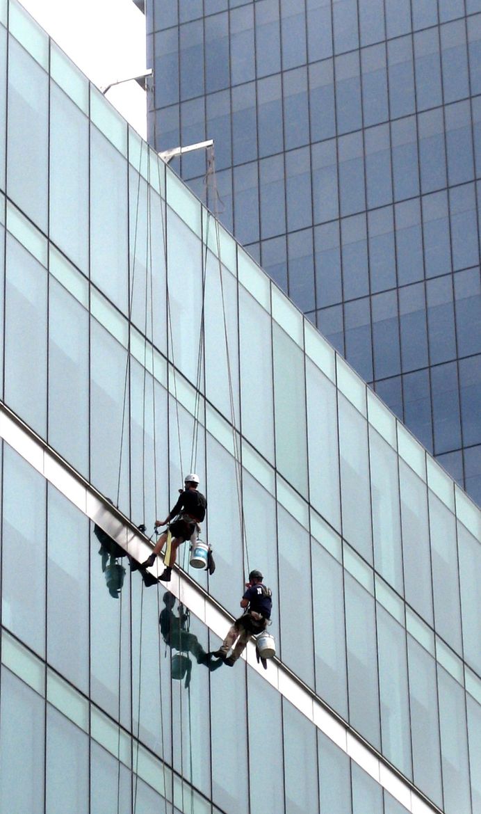 Deux hommes nettoient les fenêtres d'un grand immeuble