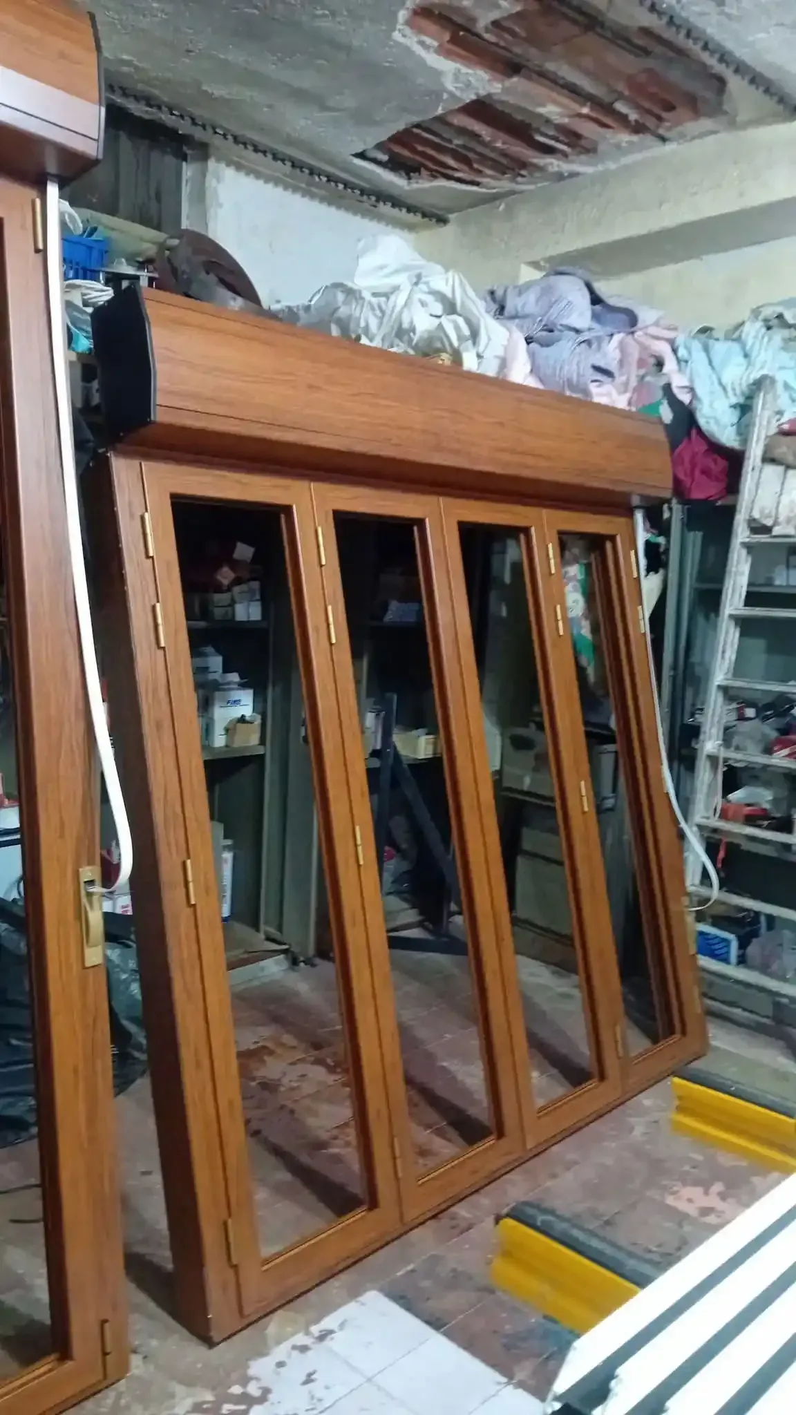 Infissi marroni con tenda avvolgibile integrata, in un ambiente disordinato come un laboratorio.