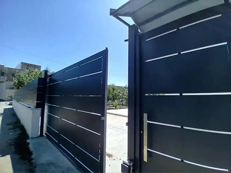 Cancello di metallo nero parzialmente aperto in una giornata di sole.