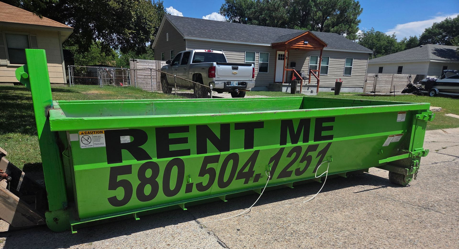 Two bright green dumpsters on a trailer and ground, with