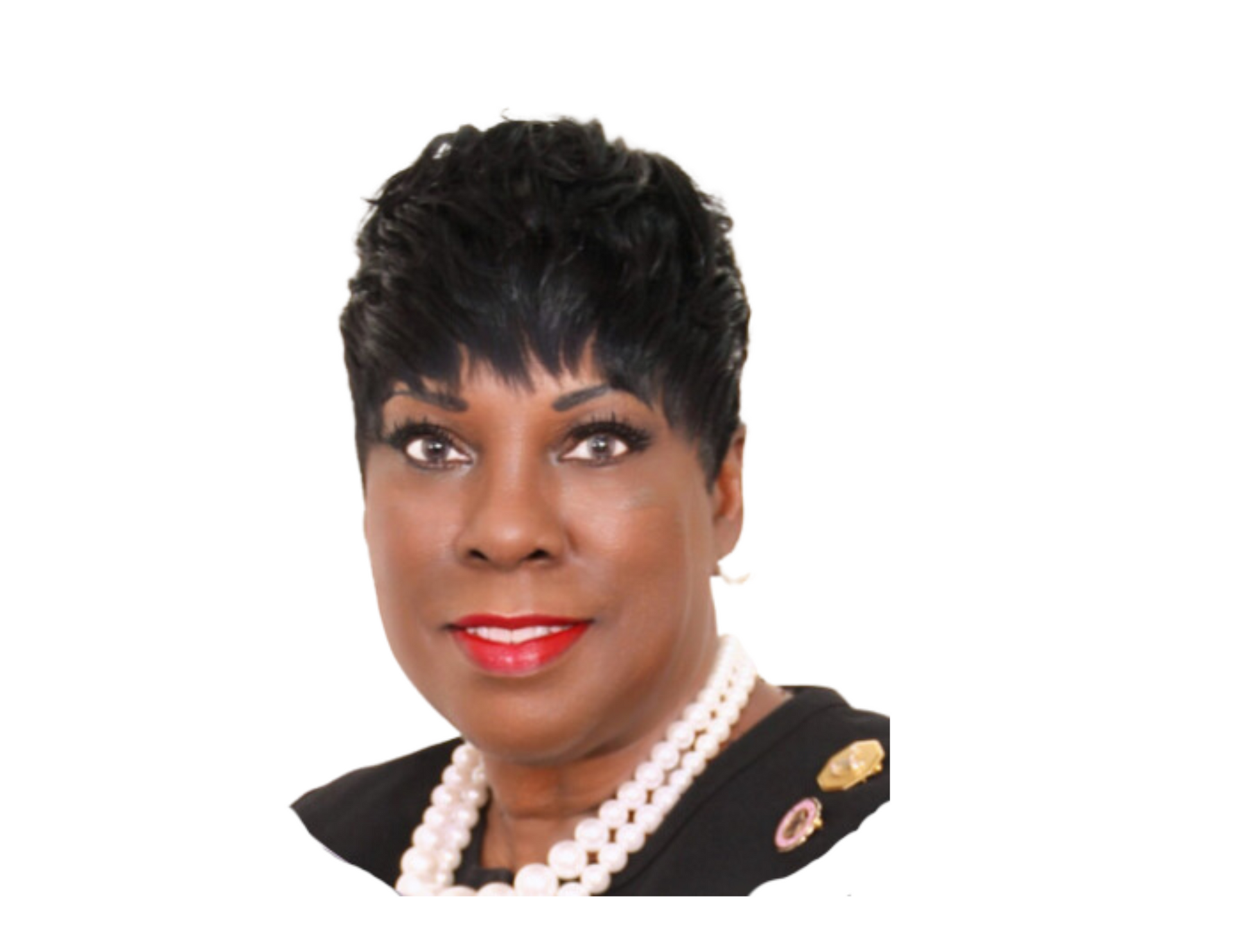 A woman wearing a pearl necklace and earrings smiles for the camera