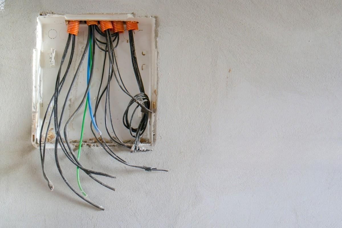 a bunch of wires are hanging from a wall in a box .