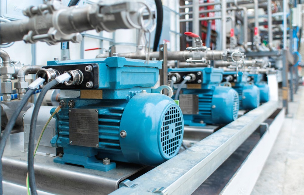 a row of blue electric motors and pipes in a factory .