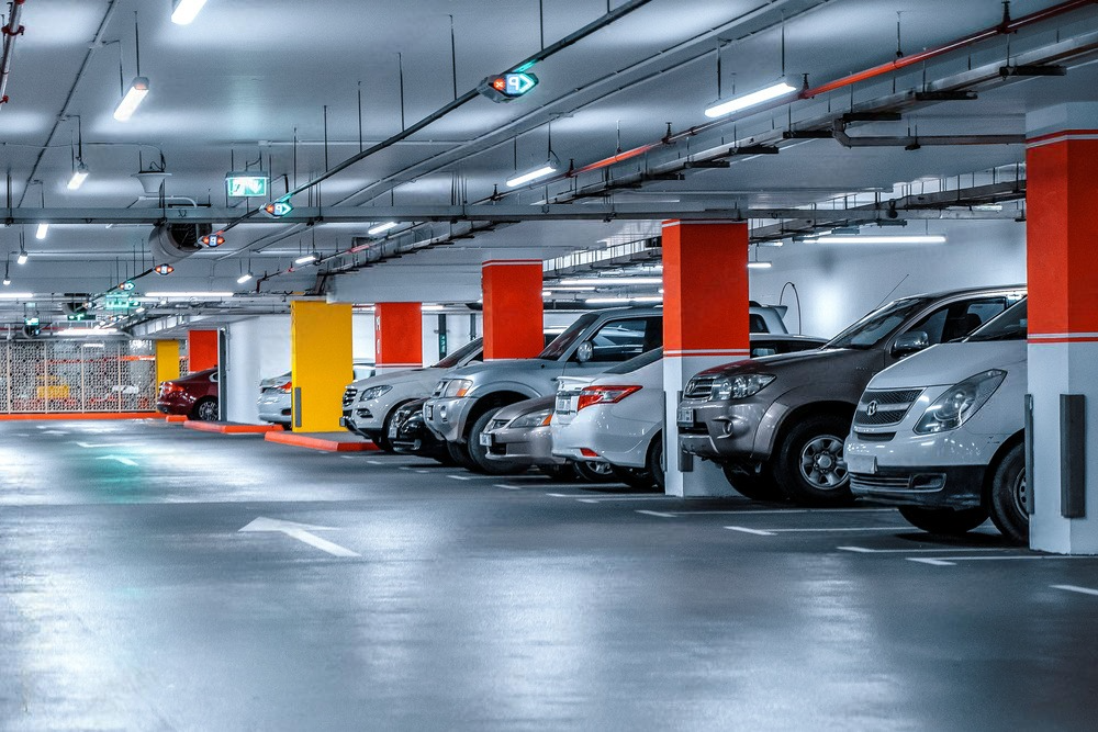 a row of cars are parked in an underground parking garage .