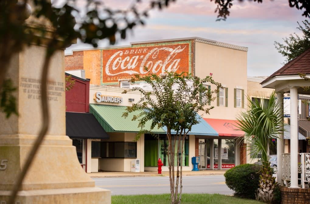 Downtown streetscape with an old Coca-Cola advertisement, shops, and a gazebo.