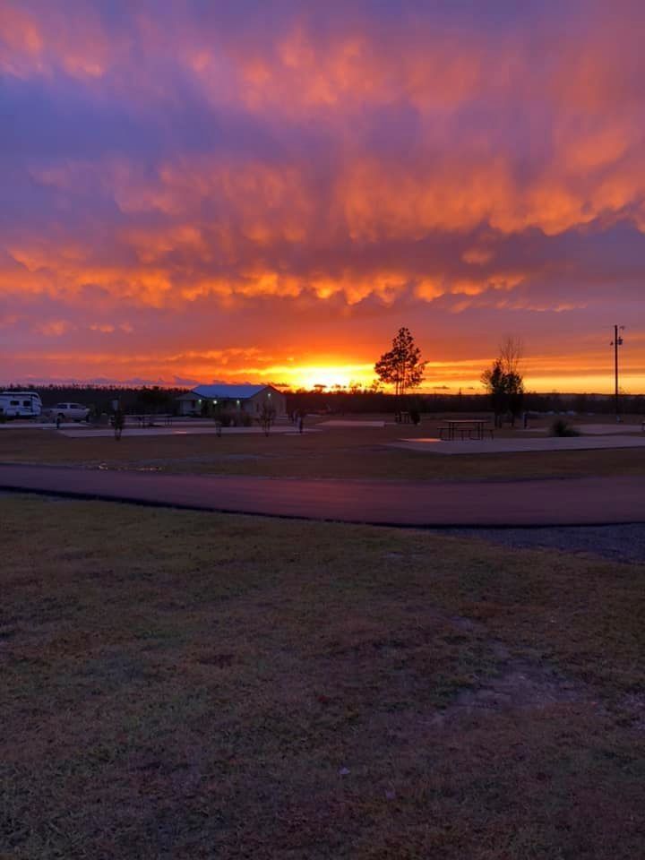 Vibrant sunset over a golf course, with orange and purple hues.