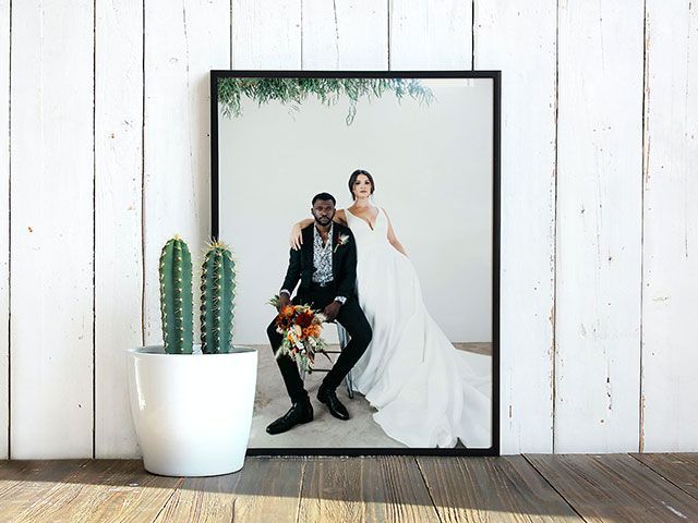 a framed poster of a bride and groom sitting next to a potted plant .