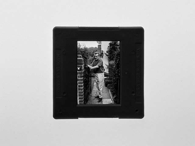 a black and white slide photo of a man standing on a balcony .