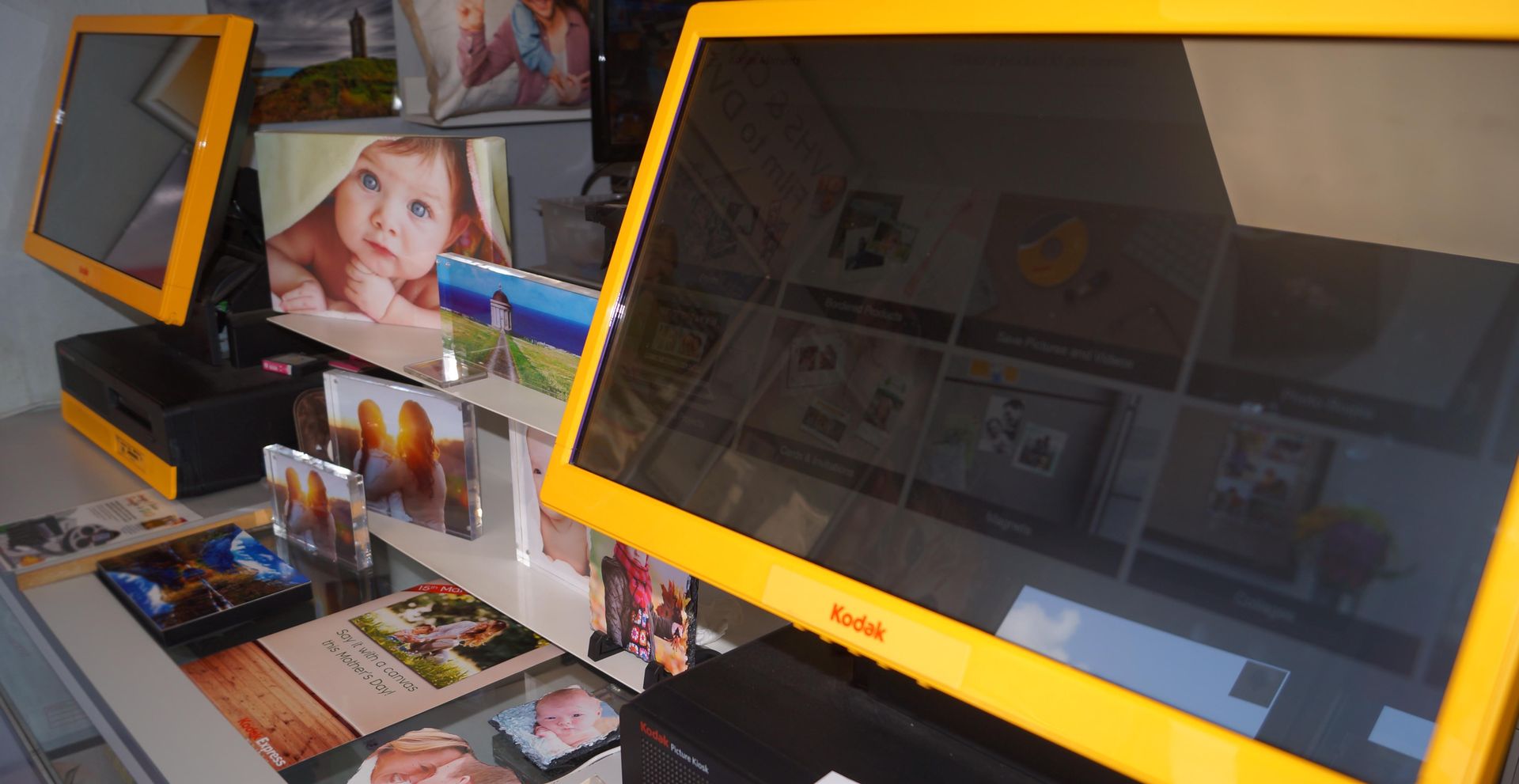 a yellow kodak photo kiosk is sitting on a table surrounded by pictures .