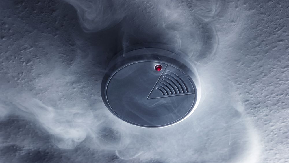 A Smoke Detector Is Surrounded By Smoke Coming Out Of It — Cairns Excel Electrics In Bungalow, QLD