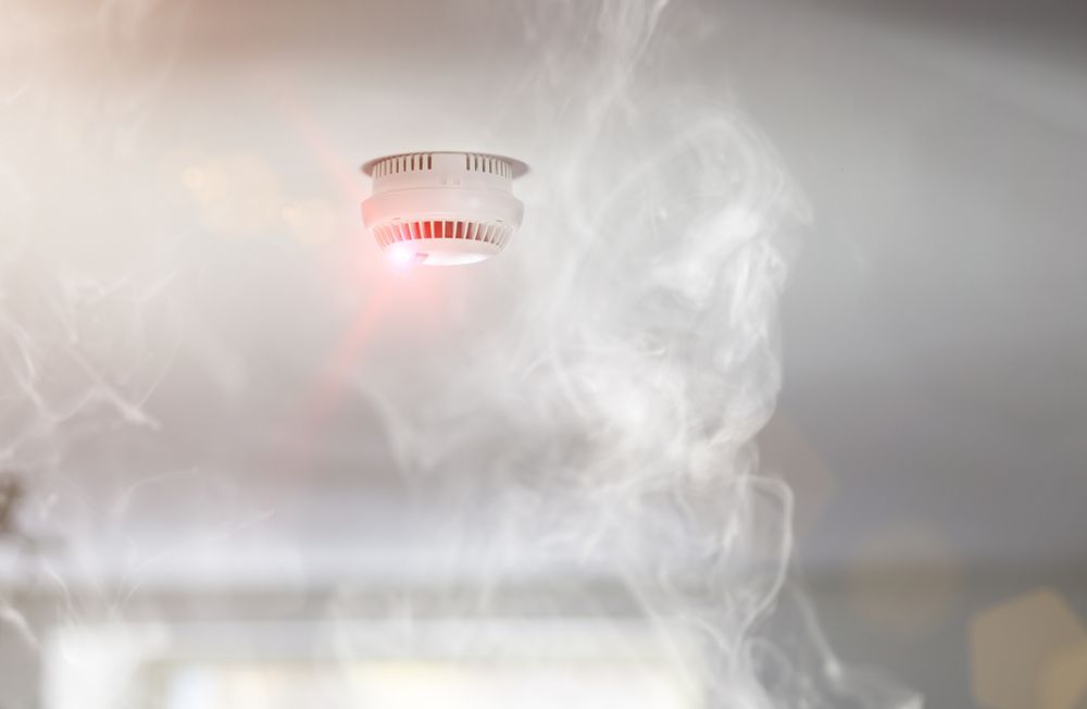A Smoke Detector On The Ceiling With Smoke Coming Out Of It — Cairns Excel Electrics In Bungalow, QLD