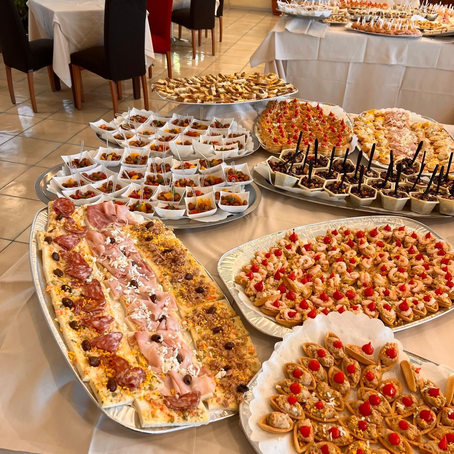 Tavolo buffet con vari antipasti, tra cui pizza, pasticcini e piccoli stuzzichini.