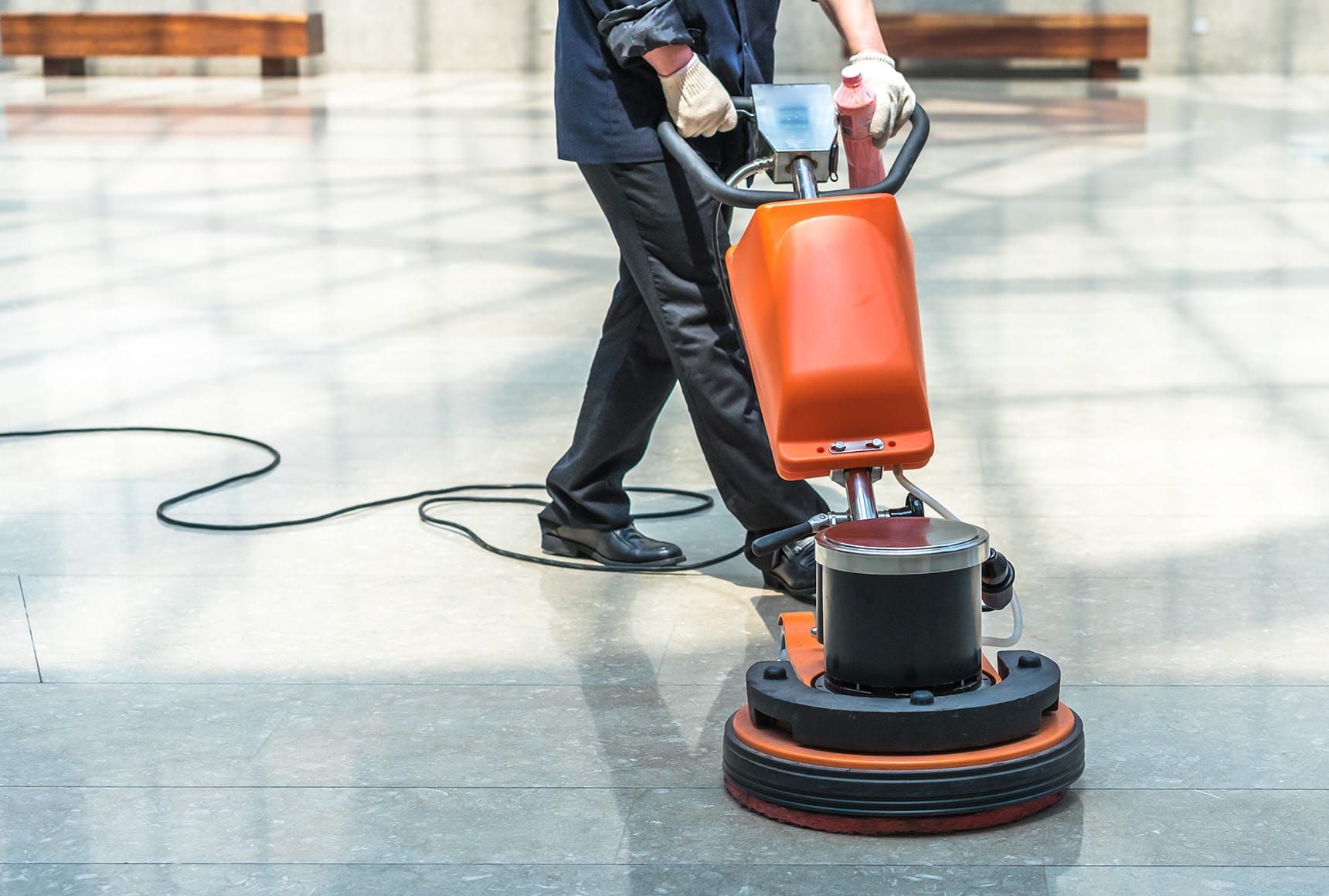 Commercial cleaner using a floor polishing machine to clean a lobby.