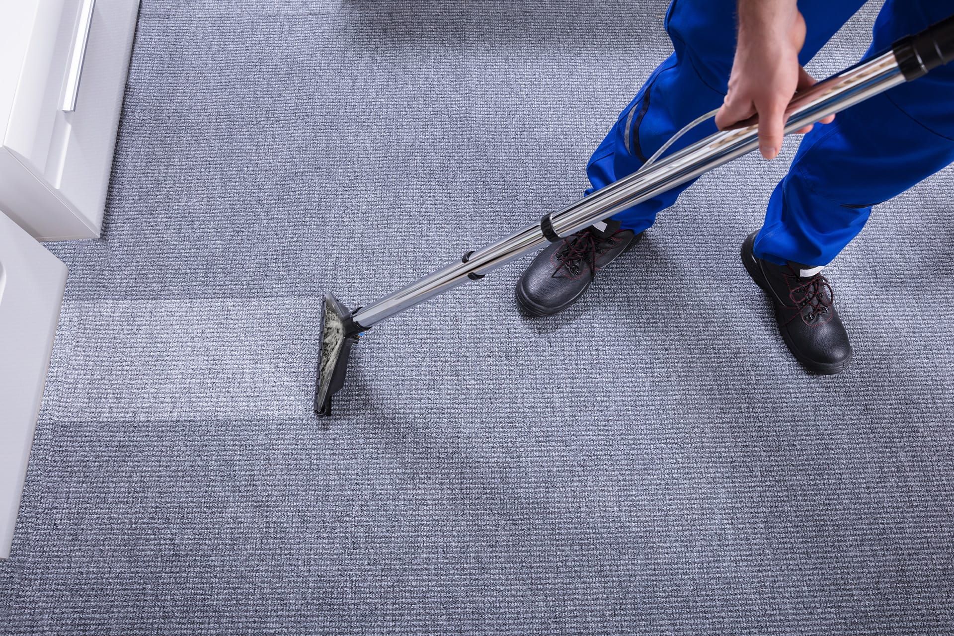 Overhead photo of Professional floor cleaner operating a carpet vacuum to clean an office floor