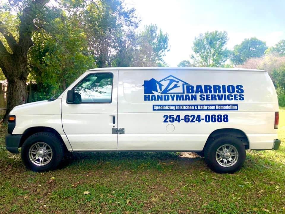 Woman in straw hat smiles, holding wine glass near a lake.