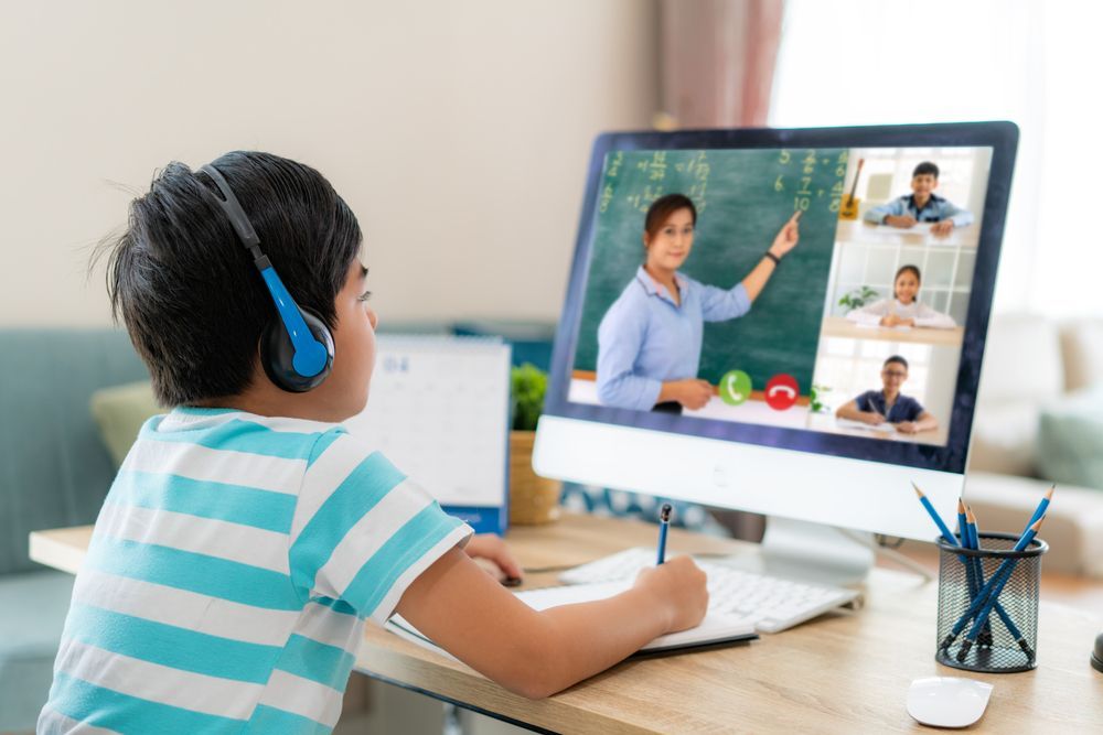 A young boy wearing headphones is sitting in front of a computer.