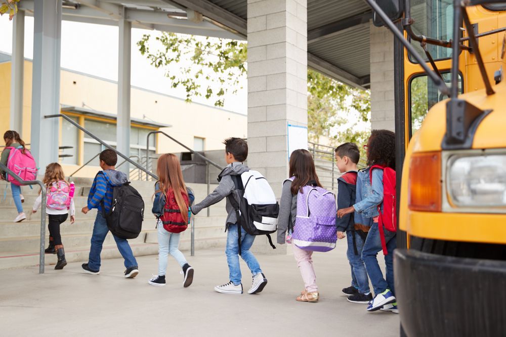 A group of children are walking towards a school bus.