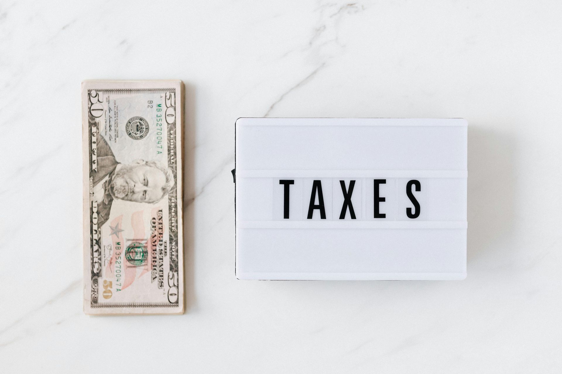 A stack of money next to a sign that says taxes.