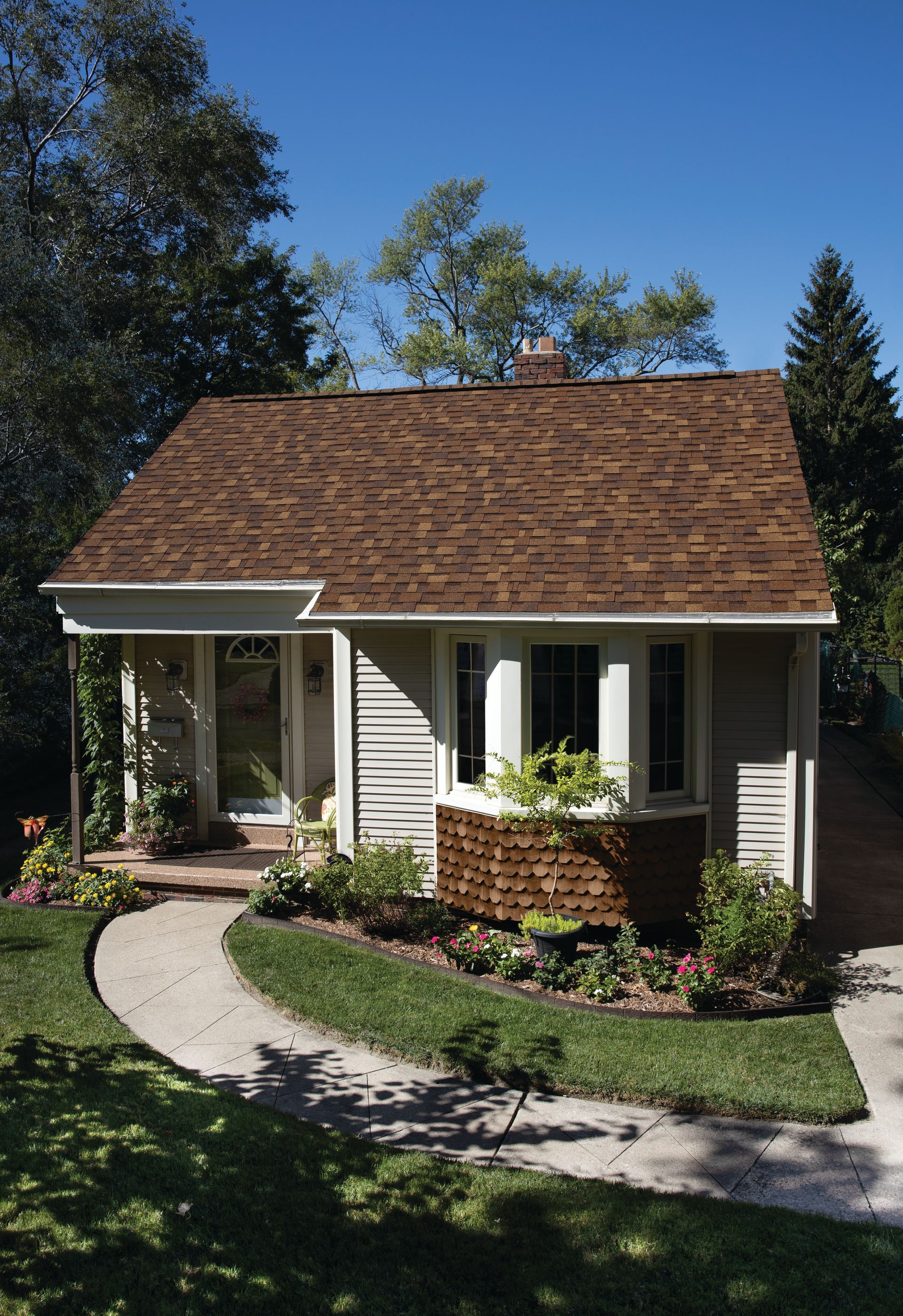 A small house with a brown roof and a walkway leading to it