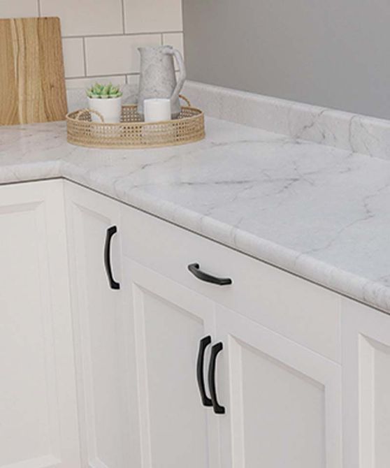 White kitchen cabinets with black handles, marble countertop, and a tray with items on it.