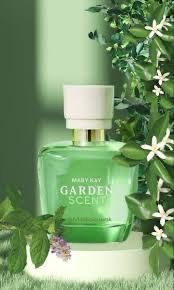 Frasco de perfume Mary Kay Garden Scent sobre un pedestal blanco, rodeado de vegetación y flores blancas.