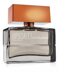 Botella de colonia Gentleman de alta gama, vidrio transparente, tapón de bronce y etiqueta blanca con marca.