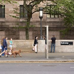 A group of people walking down a street with a sign that says subway