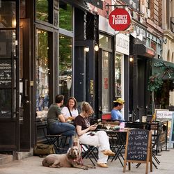 People are sitting outside a restaurant called 7th street burger