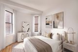 A bedroom with a bed , nightstand , dresser and two windows.