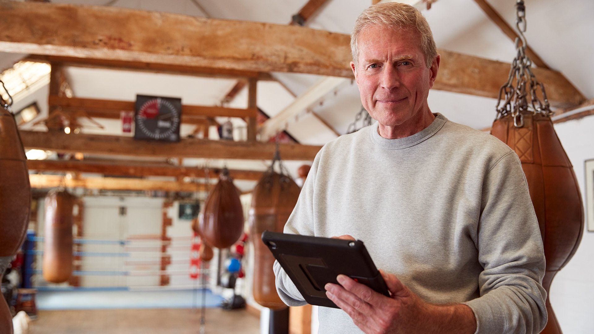 A male man smiling into the camera with a electronic tablet in his hand
