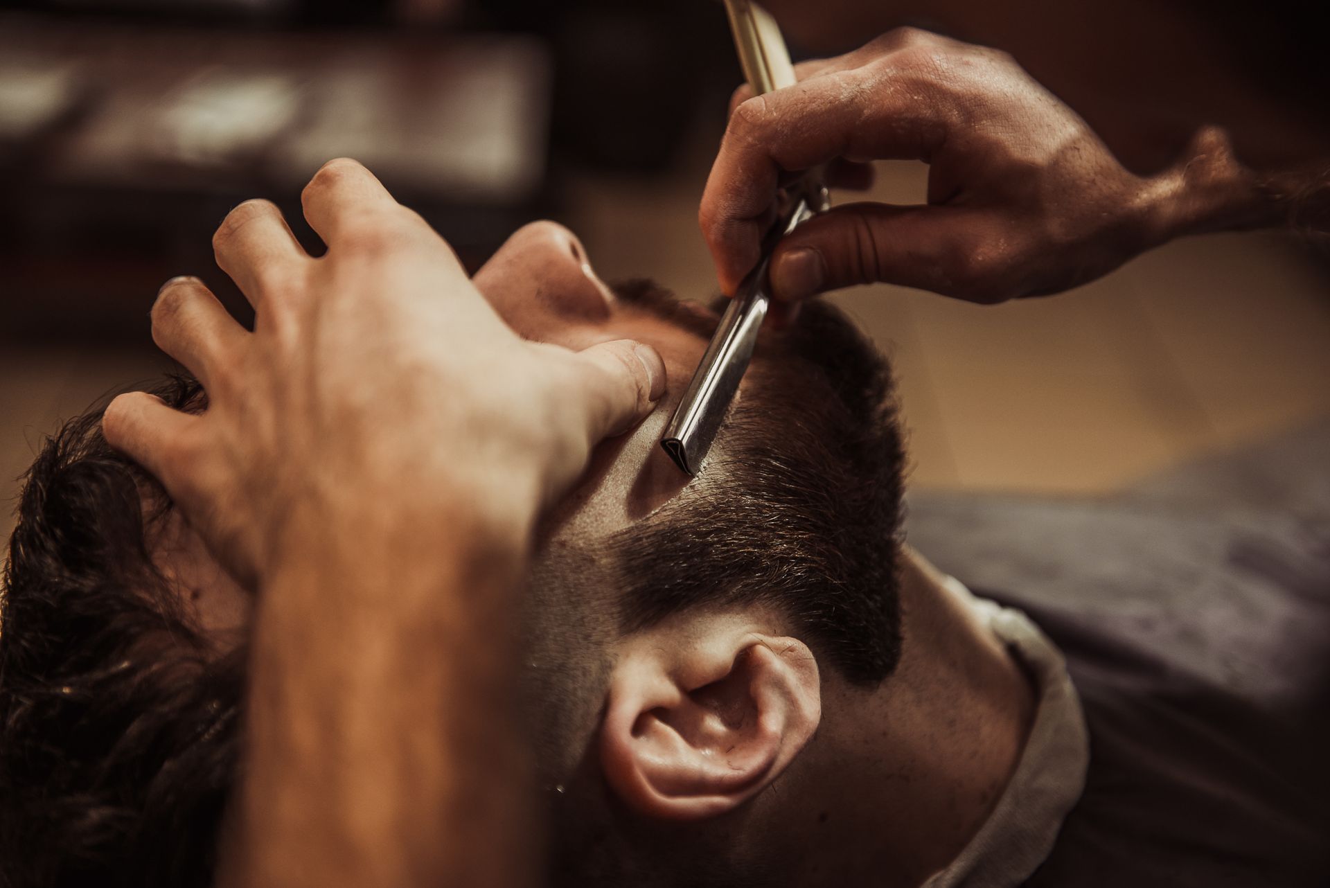 A man is getting his beard shaved by a barber with a razor.