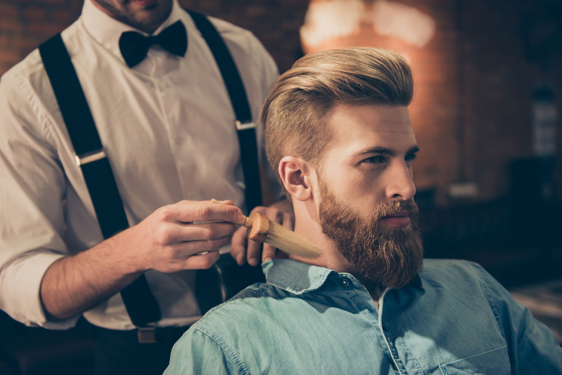 A man with a beard is getting his hair cut by a barber.