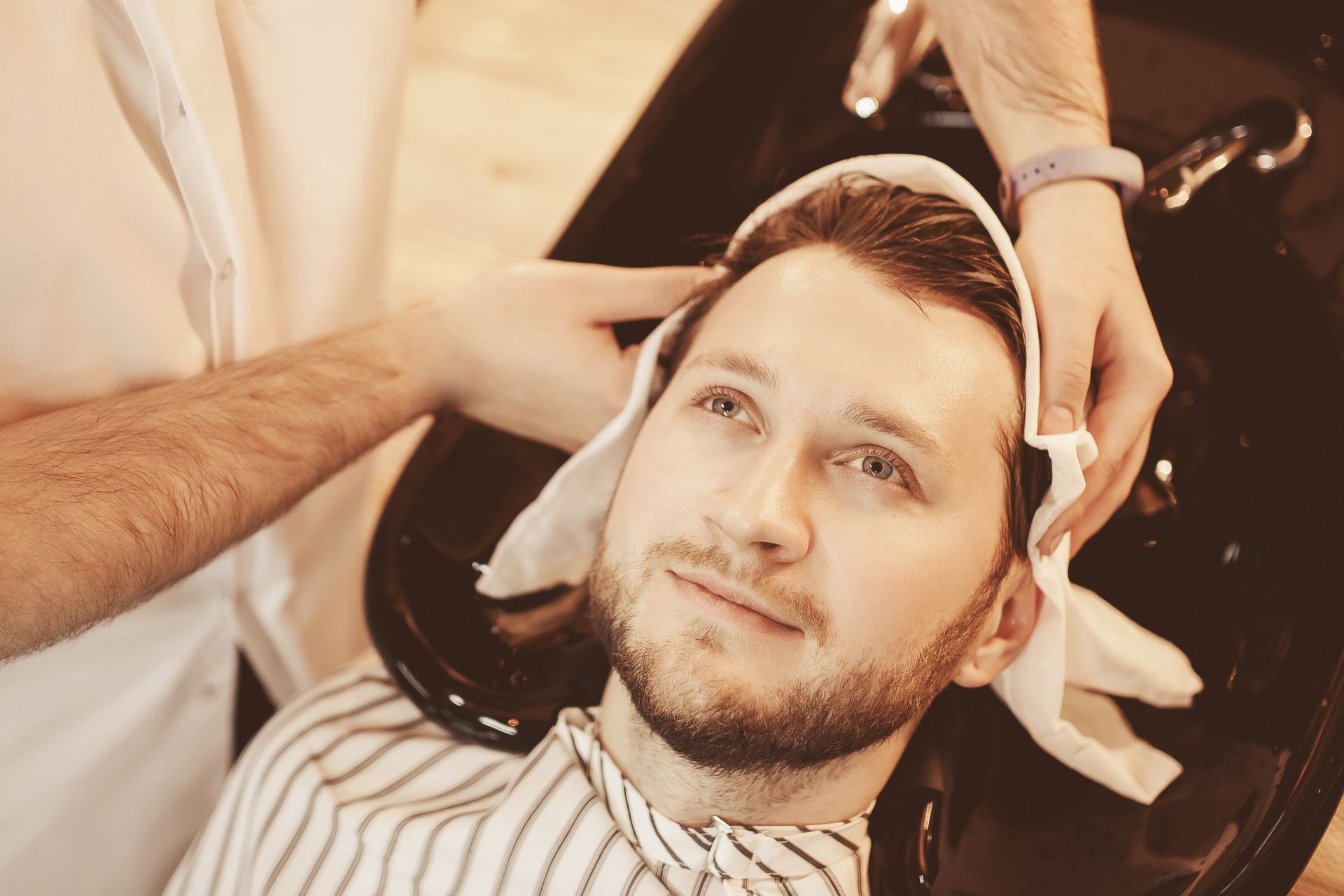 A man is getting his hair washed at a barber shop.
