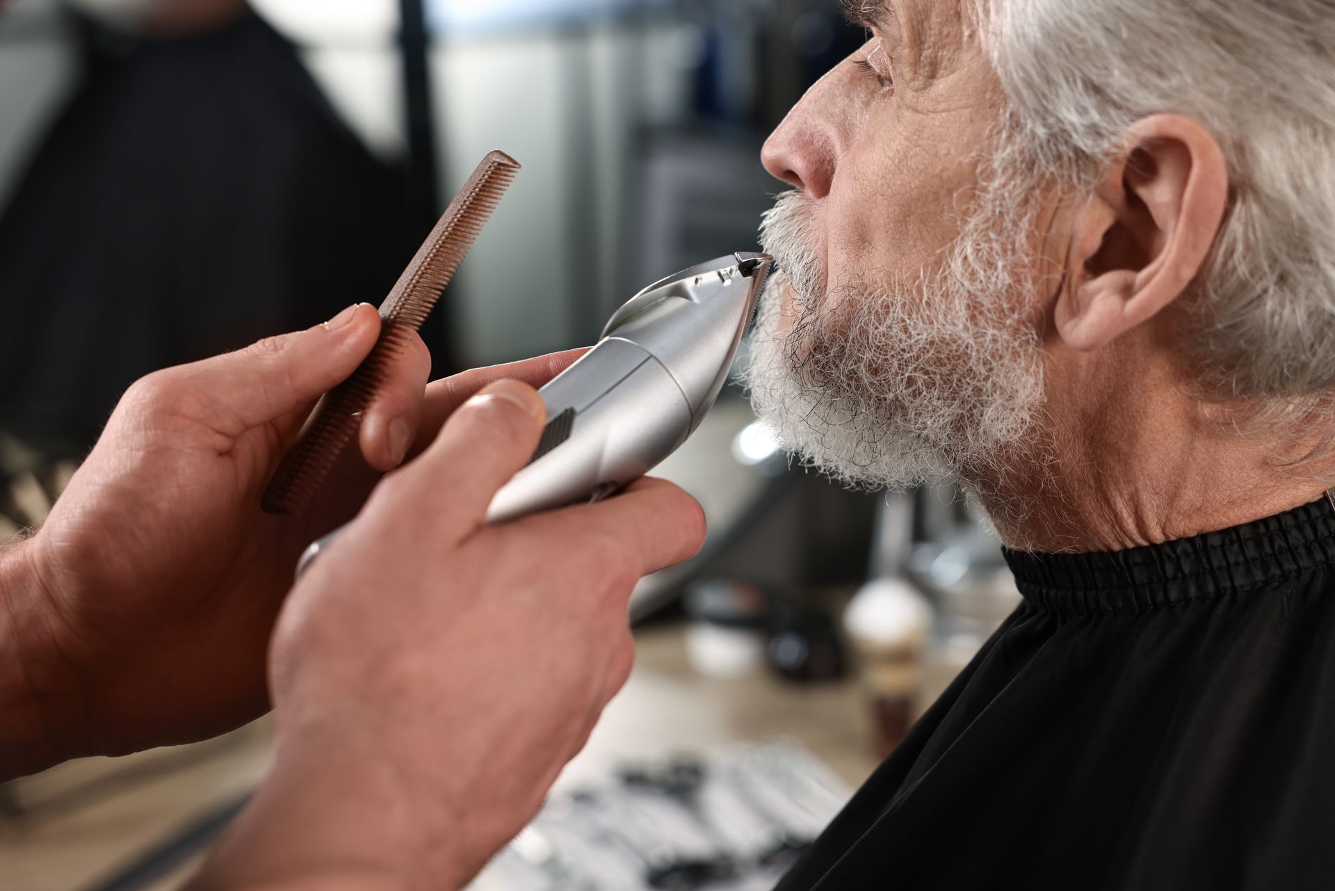 An older man is getting his beard shaved by a barber.