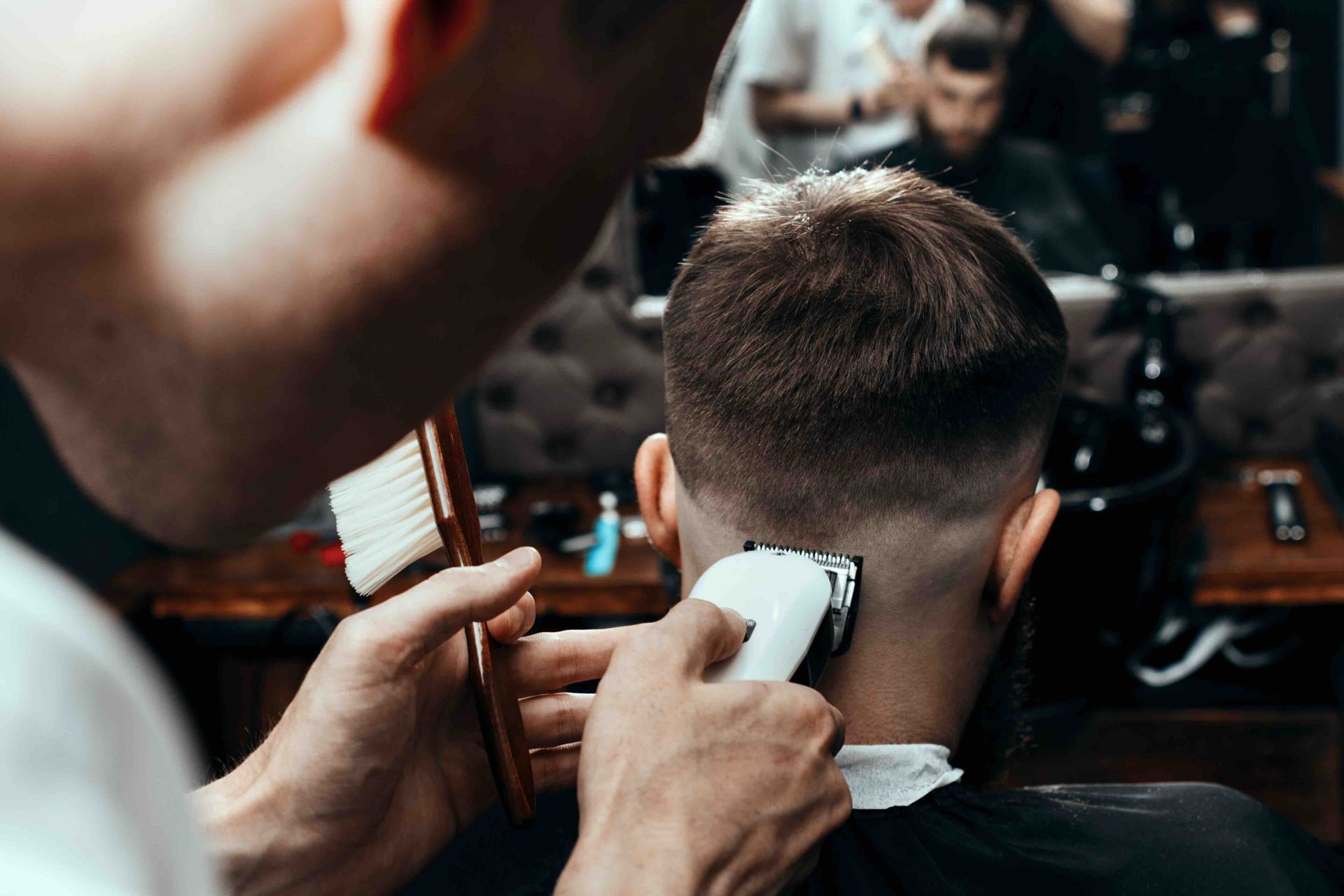 A man is getting his hair cut by a barber in a barber shop.
