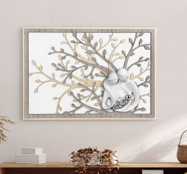 Un'opera d'arte da parete incorniciata, raffigurante una scultura stilizzata di una famiglia bianca davanti a un albero in metallo a strati color beige e grigio.