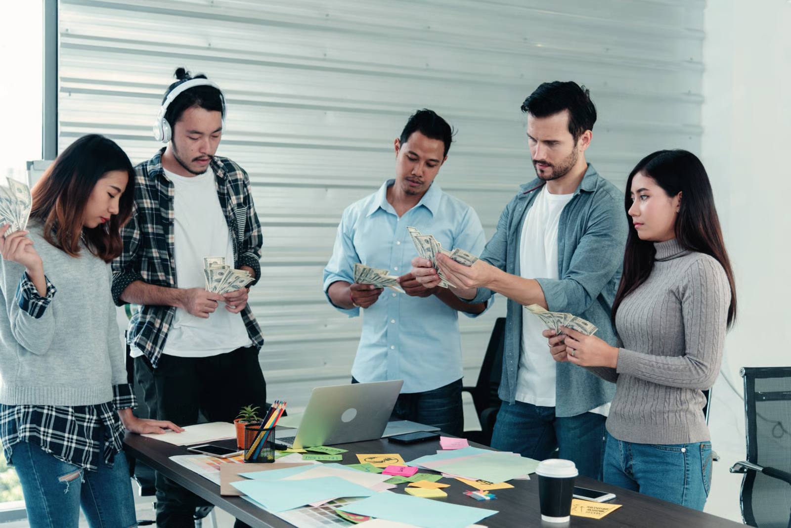 Close-up of hands in business attire using a smartphone while pointing at a bar graph and a laptop.